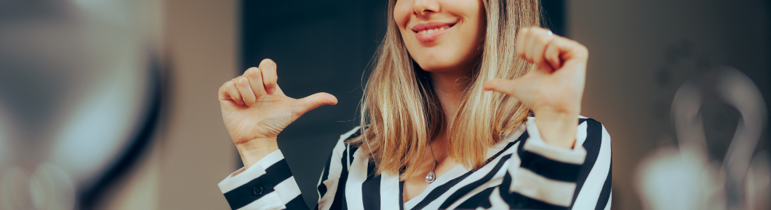 smiling woman pointing at herself with two thumbs