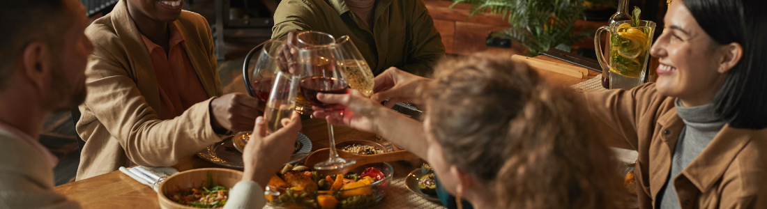 group of people toasting at a dinner table full of food